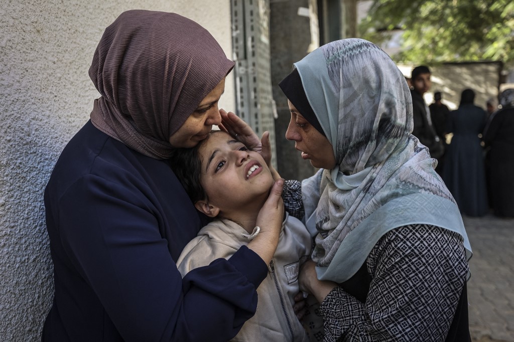 Women comfort the daughter of Akram Yassin and his wife Dina, who were killed in an Israeli strike on a residential building, during their funeral in Gaza City on October 20, 2026. AFP